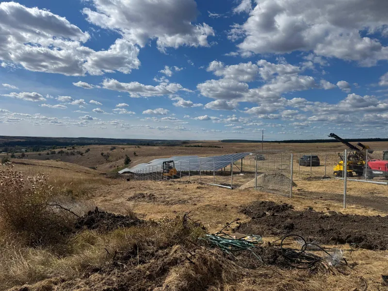 Site works beside the fenced panel area, with machinery on site